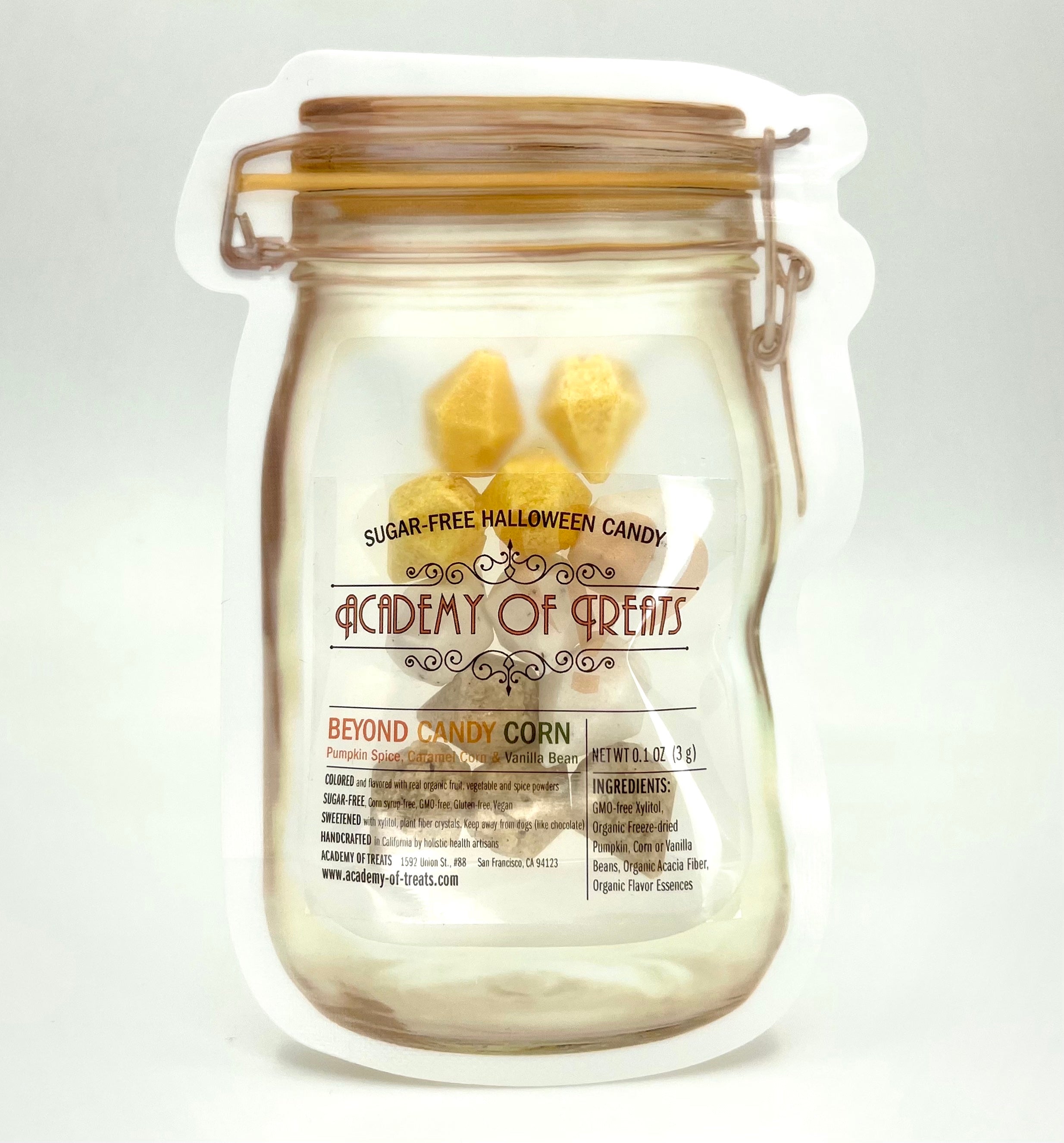 A clear glass jar containing sugar-free candy corn with labels indicating 'Academy of Sweets', 'Beyond Candy Corn', and 'Sugar Free Halloween Candy'.